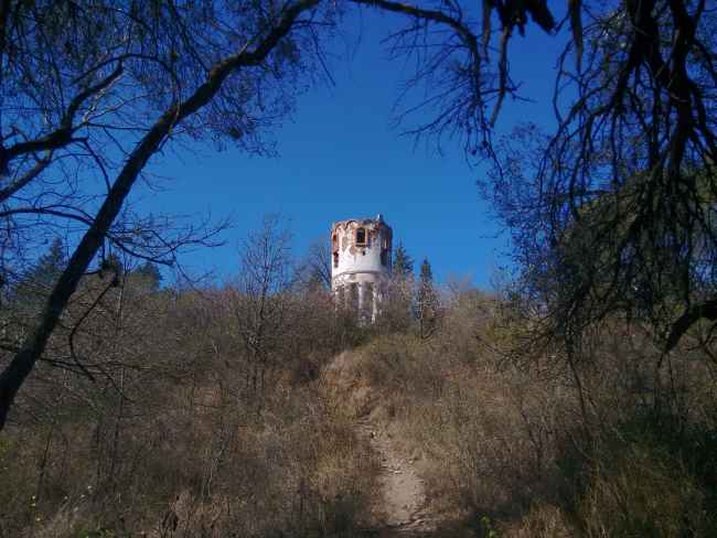 torre antigua deteriorada en una colina al lado de un sendero en la montaña